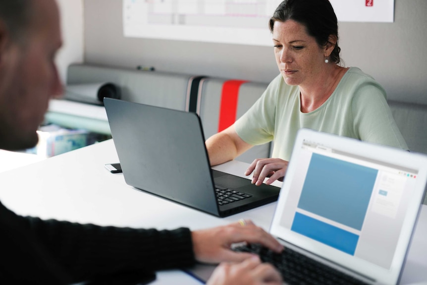 A woman looks downcast while on her computer in an office