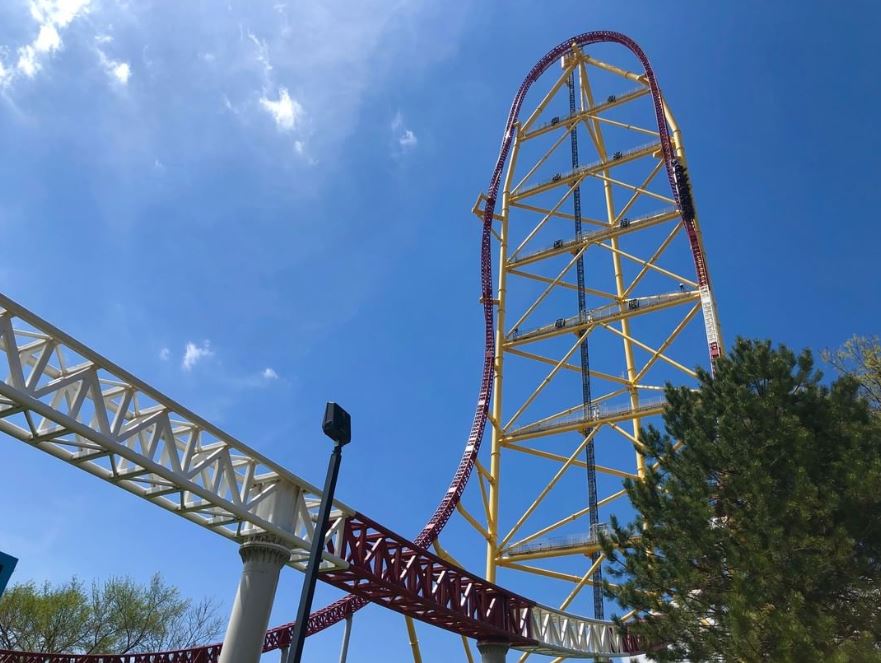 A red and yellow rollercoaster with a blue sky in the background.