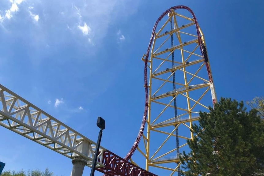 A red and yellow rollercoaster with a blue sky in the background.