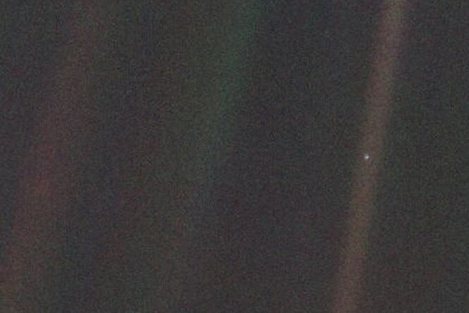 A tiny speck of light in an otherwise dark image. The speck is Earth.