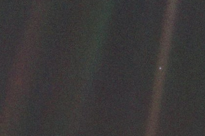 A tiny speck of light in an otherwise dark image. The speck is Earth.