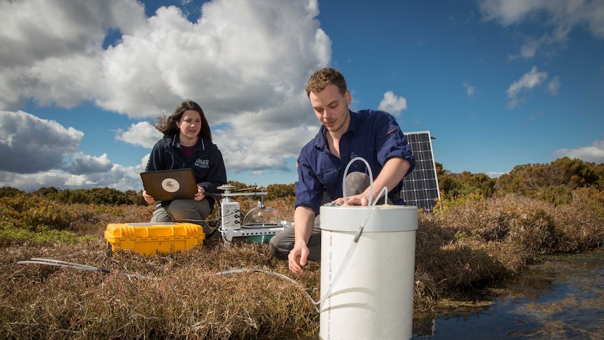 Deakin University researchers Katy Limpert and Quinn Ollivier take gas samples from a farm dam.