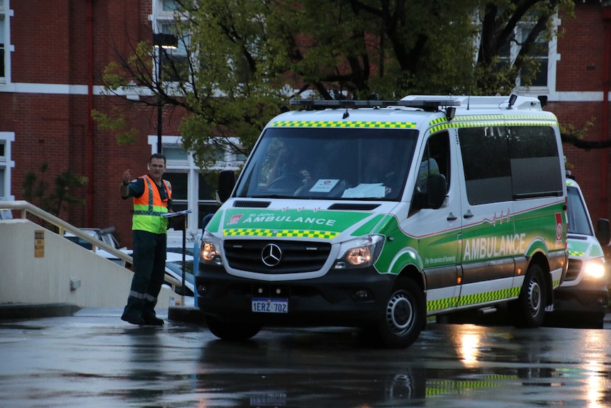 A St John Ambulance leaves Princess Margaret Hospital, directed by a paramedic in a hi-vis vest