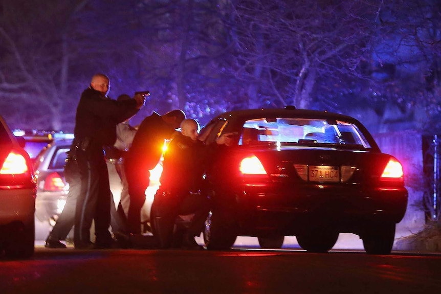 Police stand with guns drawn behind squad cars in Watertown