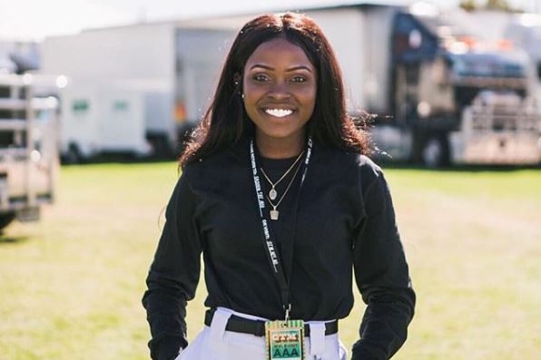 Elsy Wameyo standing up with her hands in her pockets wearing a black long-sleeved top and white jeans