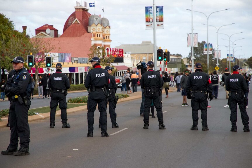 A number of uniformed police officers stand on Kalgoorlie's main street.