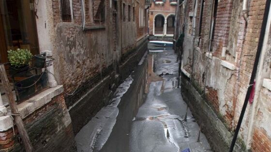A boat lies immobile on mud in a Venice canal