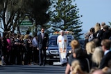 Mourners form a guard of honour as the funeral procession of John McCarthy makes its way down Ocean Beach Road.