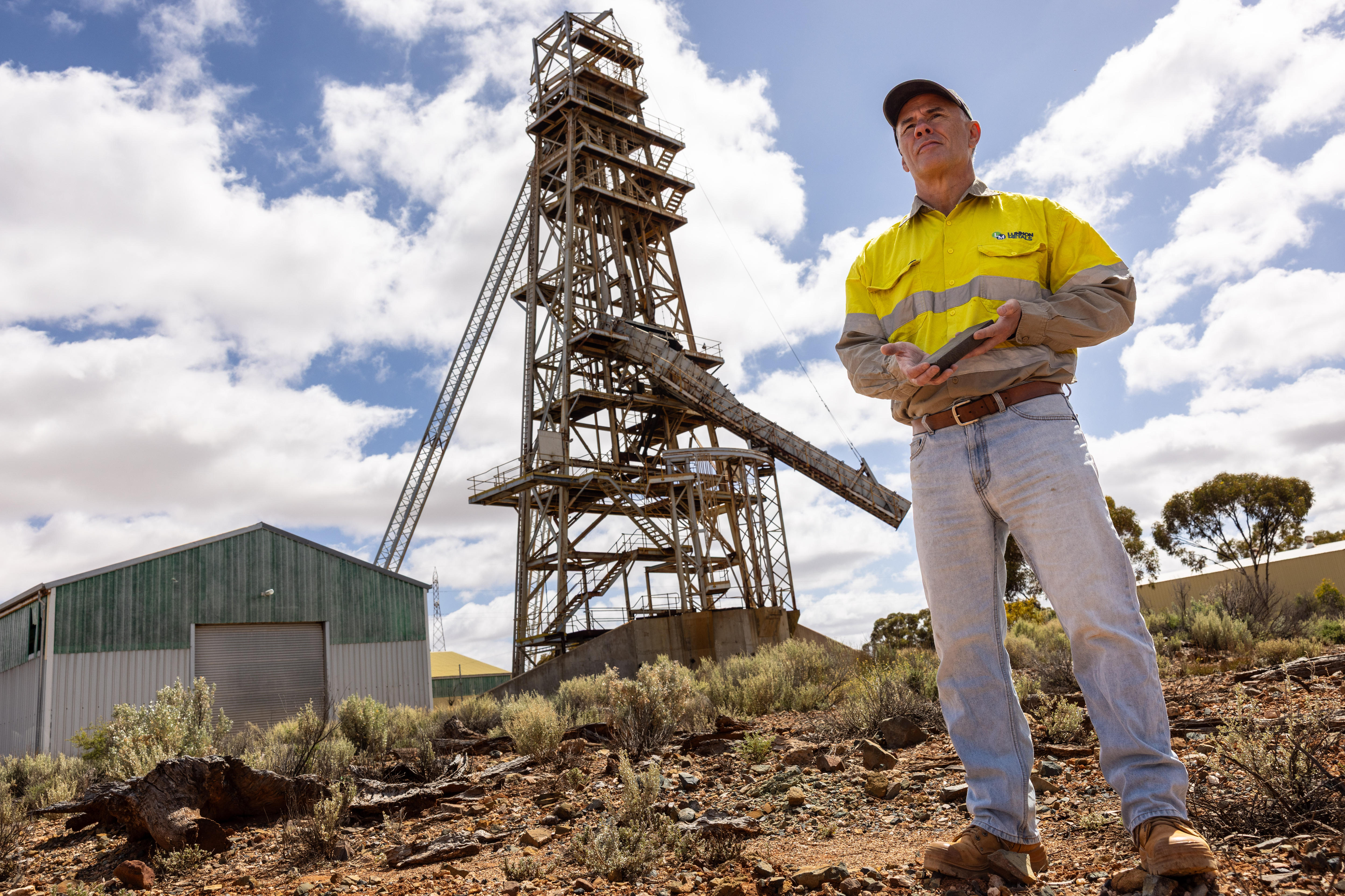 A geologist standing in front of a nickel mine headframe and shaft near Kambalda.  