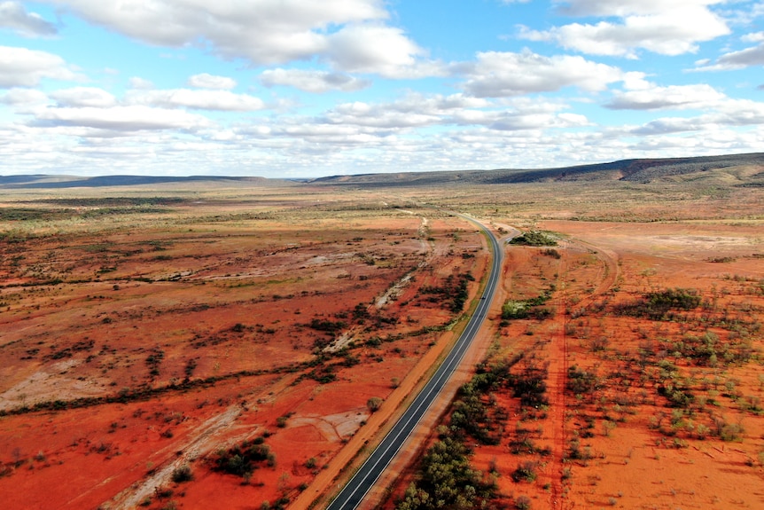 An electric vehicle on a highway in the red dirt outback