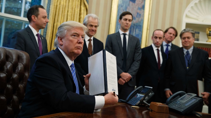 President Donald Trump shows off a signed executive order in the Oval Office.