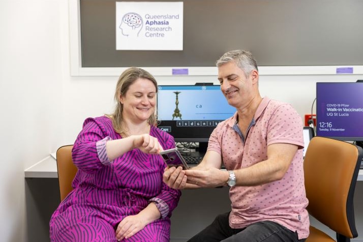 QARC researcher Jessica Campbell showing a person with aphasia an app on a phone.