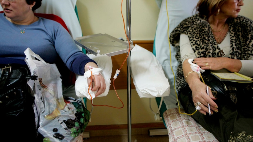 Two women in hospital receiving intravenous chemotherapy treatment.