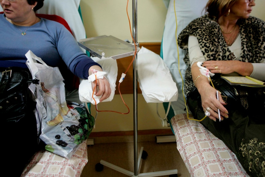 Two women in hospital receiving intravenous chemotherapy treatment.