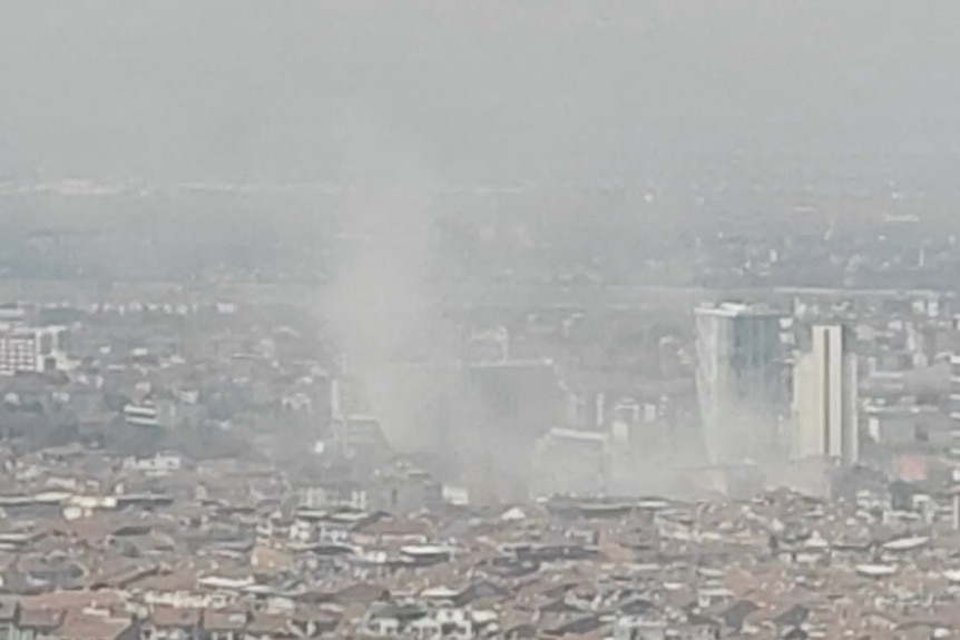 Dust is seen in the air above the city where a building collapsed.