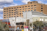 A hospital building seen from across a busy road.