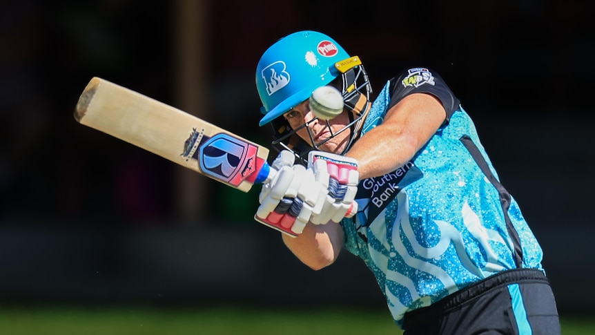 A Brisbane Heat WBBL cricketer is partially obscured by the ball as she hits it away high on the leg side.