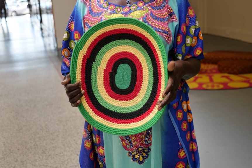 The women create the woven discs using grass straw and yarn.