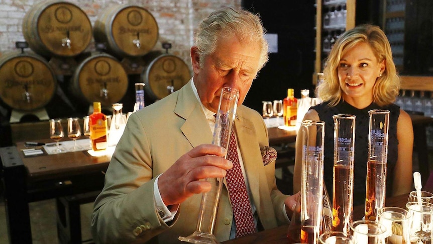 Prince Charles sniffing a beaker of rum inside Bundaberg Rum Distillery