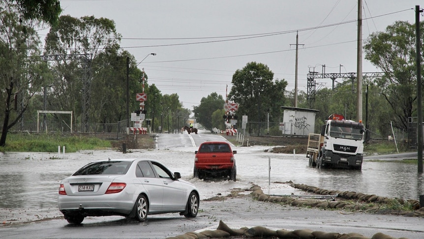 Cars cross a flooded road.