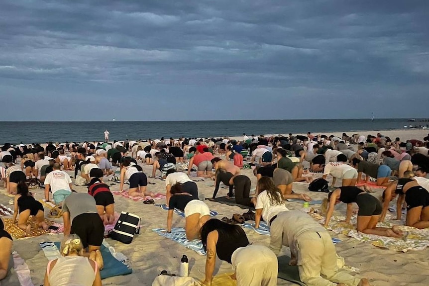People performing yoga on a beach.