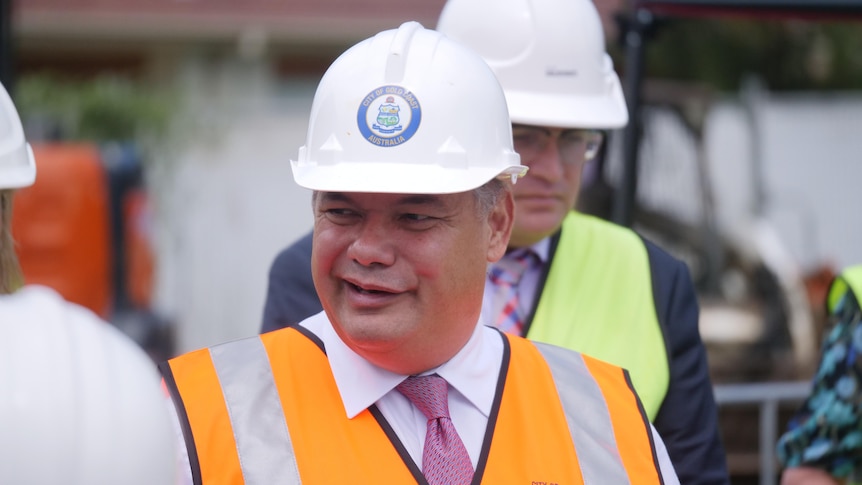 A smiling man in a hard hat and high-vis.