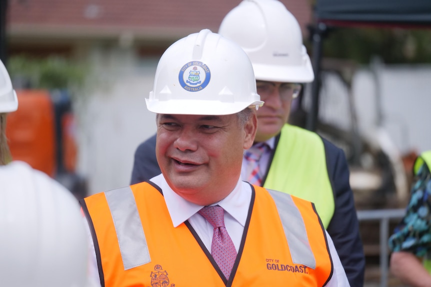 Smiling politician wearing a hard hat and peaked.