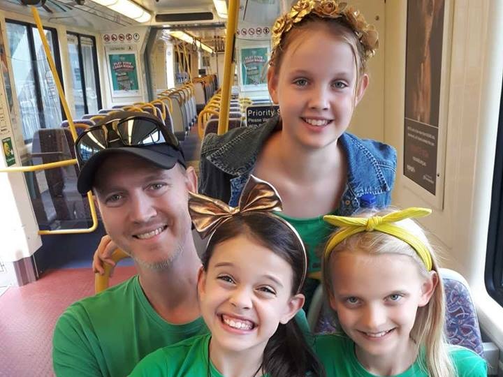 Man sits with his three young girls on light rail