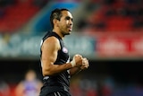 An Indigenous AFL footballer pumps his fists and smiles after kicking the final goal of the game.
