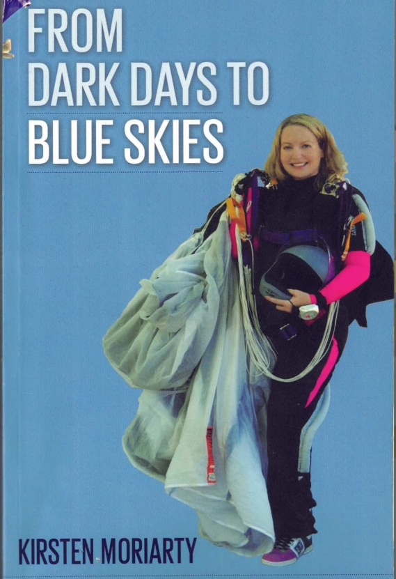 La portada de un libro con el título. "De días oscuros a cielos azules" y una imagen de una mujer rubia sonriente sosteniendo un paracaídas.