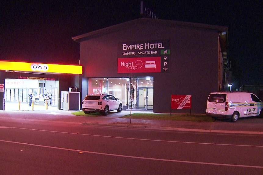 The front of a hotel with a sign reading Empire Hotel, with a BWS bottle shop to the left and a police car parked in front