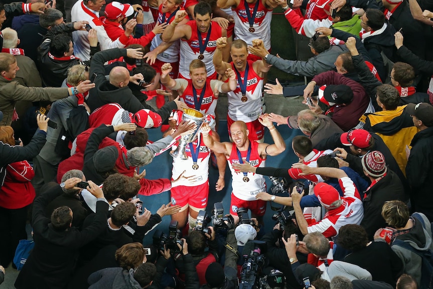 Jarrad McVeigh and Adam Goodes walk down the players tunnel with the premiership cup.