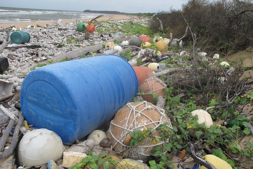 Buoys, nets, plastic drums and bottles at the top of the tide line on a remote far north Queensland beach.