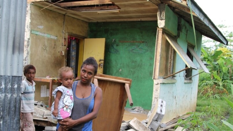 Zinnia and her baby in front of their damaged house in Kirakira, Solomon Islands.
