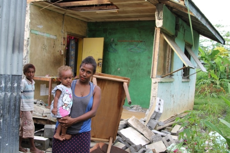 Zinnia and her baby in front of their damaged house in Kirakira, Solomon Islands.