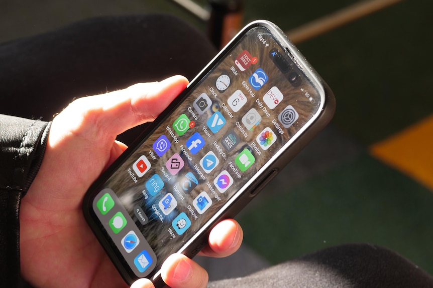 An iPhone held in a hand focusing on the home screen.