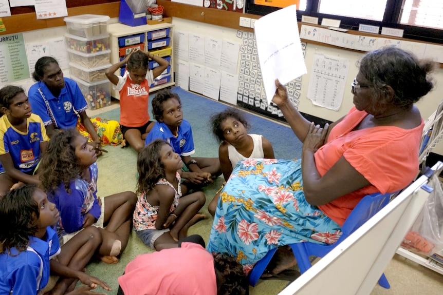 A group of students sit in a classroom  listening to a teacher.