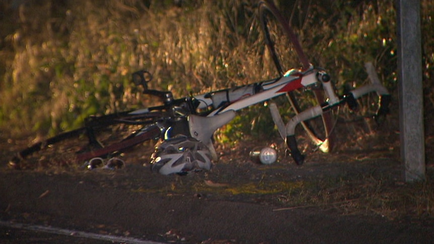 A bike, helmet and sunglasses lay on the side of the road after a crash.