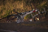 A bike, helmet and sunglasses lay on the side of the road after a crash.
