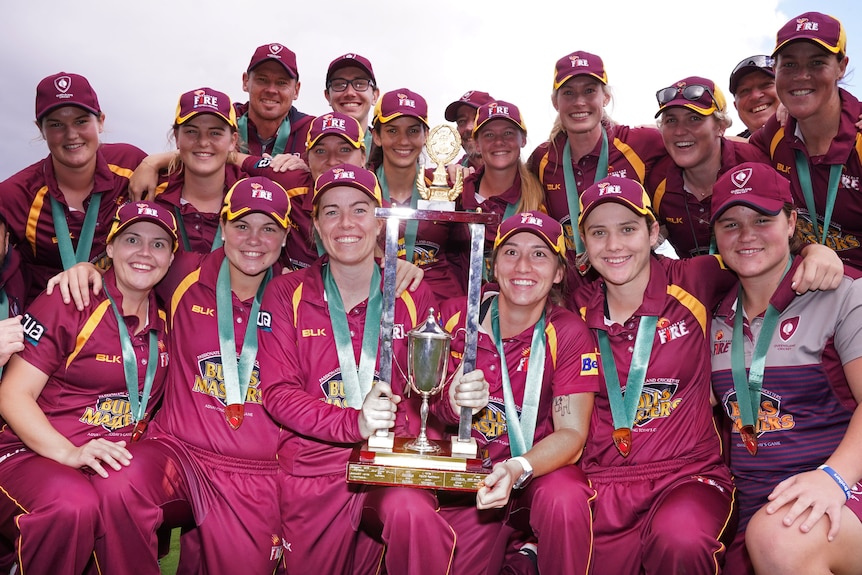 Queensland Fire players hold the Women's National Cricket League trophy.