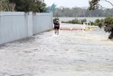 Cyclist rides along flooded bike path next to the Swan River in Perth.