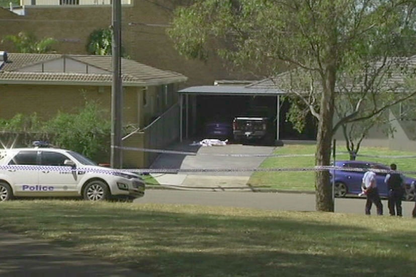 The man's body covered by a white sheet on a driveway outside a suburban home.