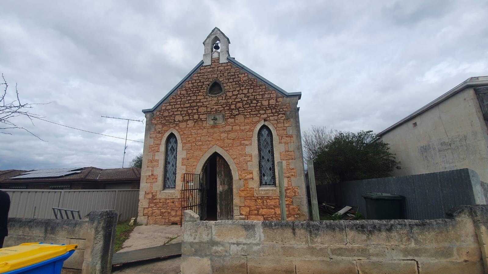 A small stone church with a wall at the front