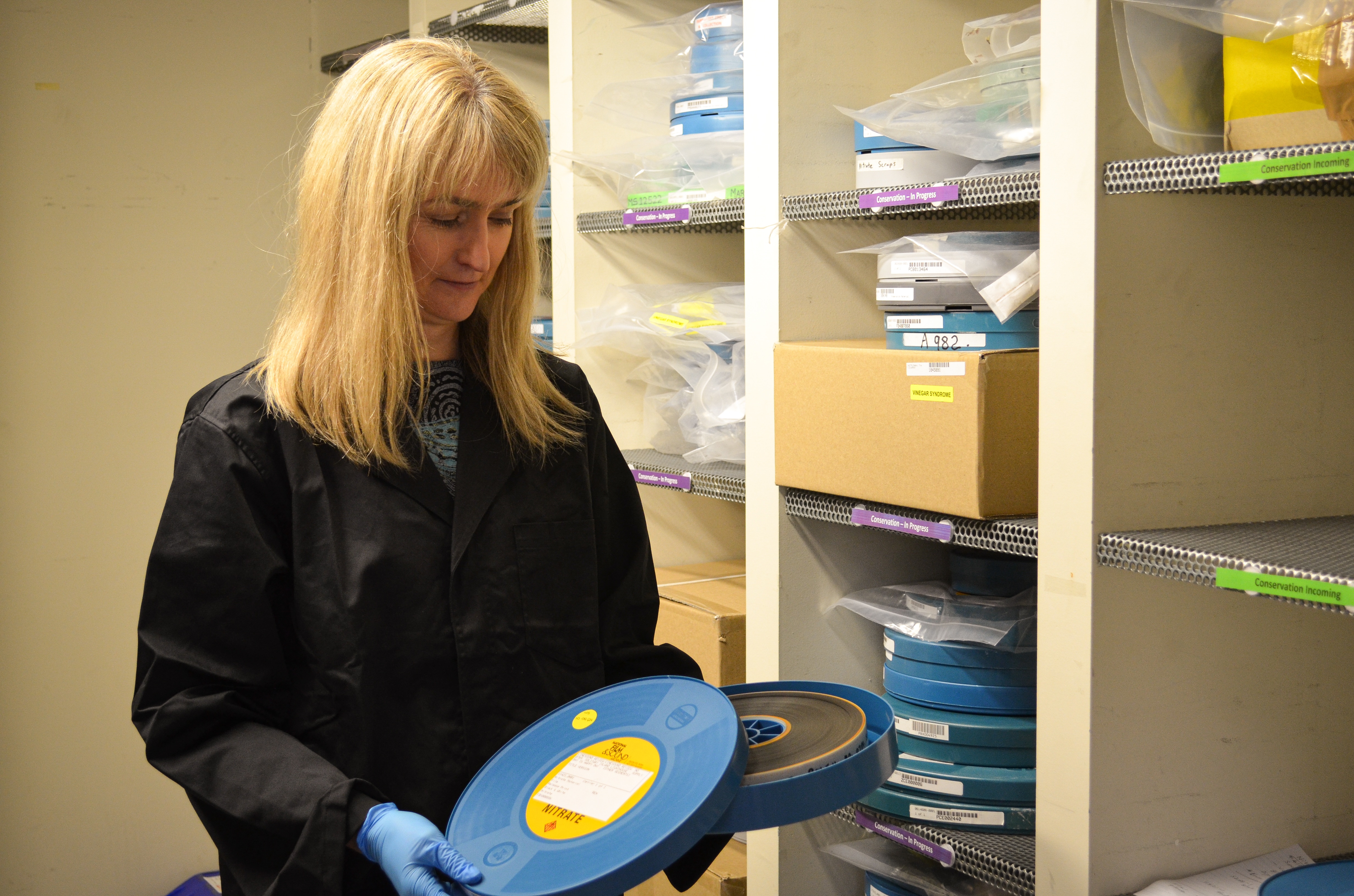 Dr Lewincamp has long blonde hair and is holding a bright blue cannister of film reel