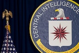 An American flag on its flagpole next to the seal of the Central Intelligence Agency