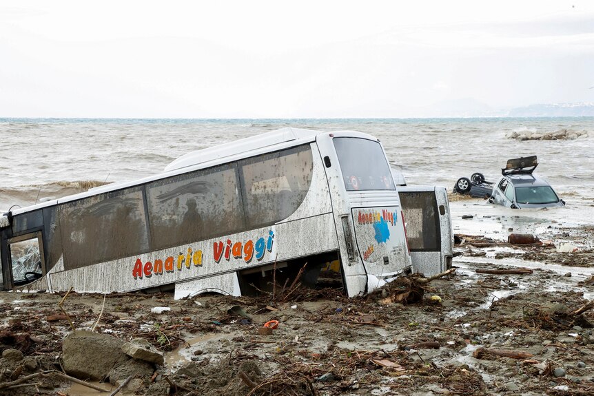 Damaged cars are seen in the sea following a landslide.