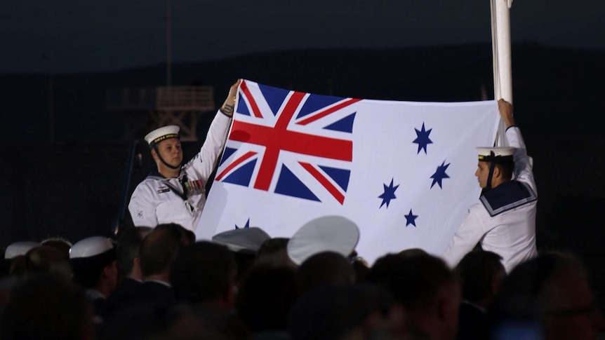 Naval officers hold the Australian white ensign flag as the sunset ceremony ends on the Albany foreshore