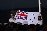 Naval officers hold the Australian white ensign flag as the sunset ceremony ends on the Albany foreshore