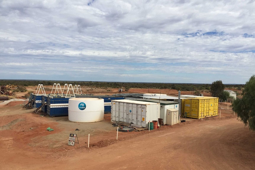 Several large shipping containers and portable buildings in an arid landscape