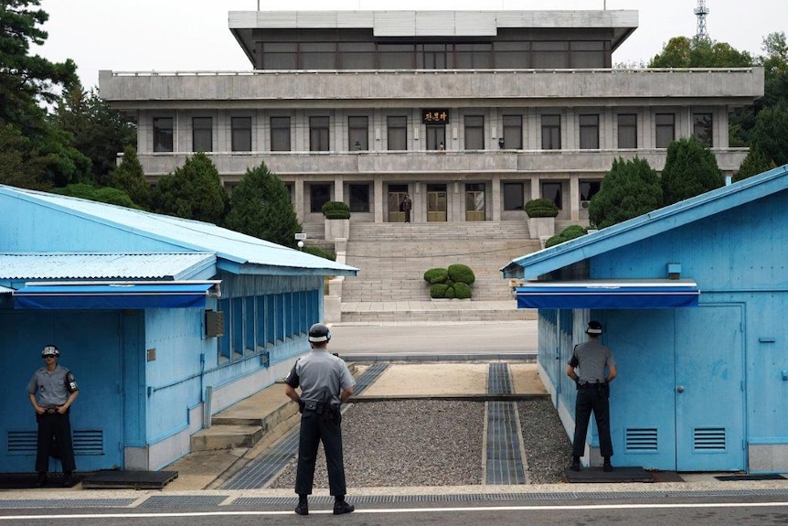 Soldiers stand with their backs facing the camera in the DMZ's Joint Security Area